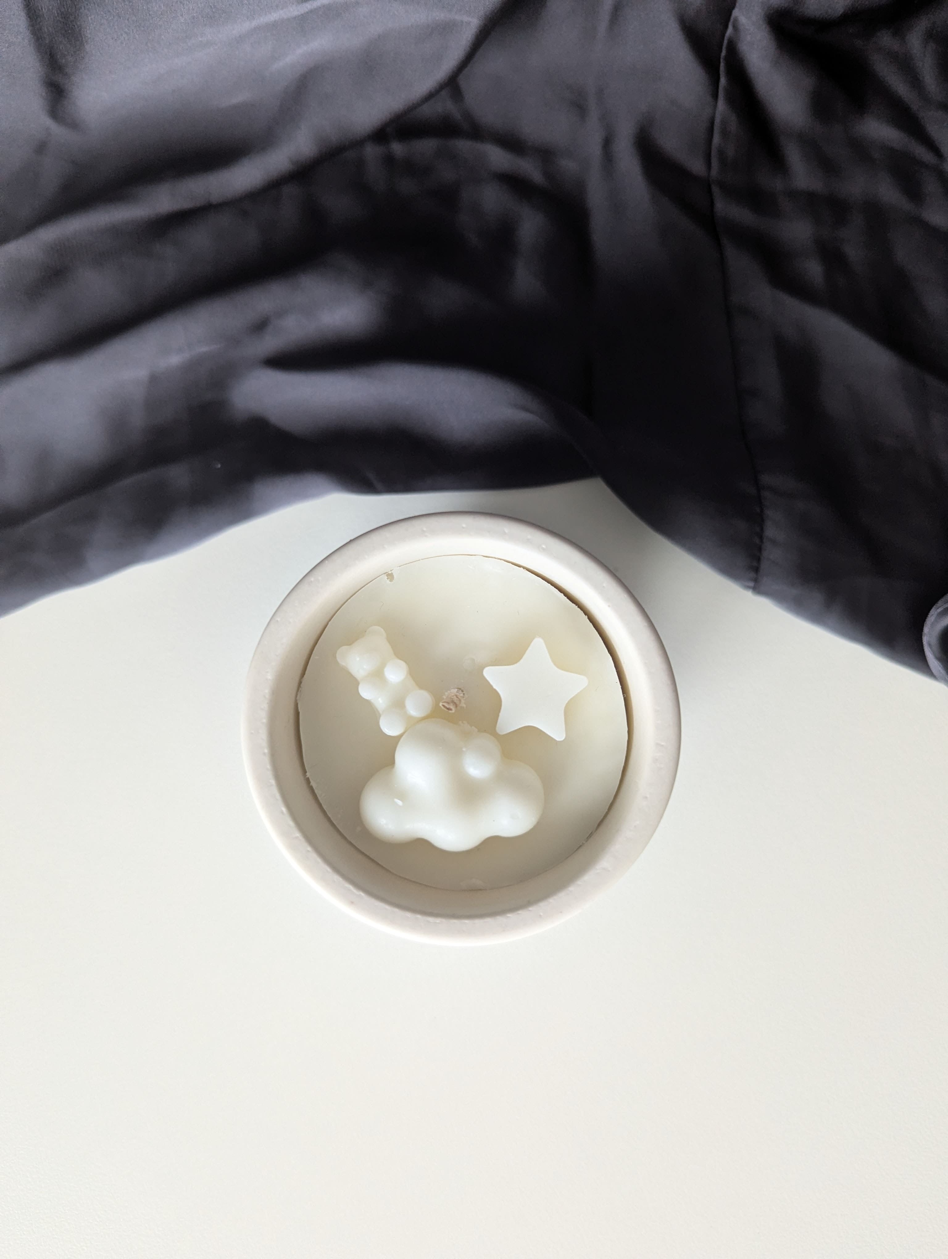 Bougie artisanale parfumée vue du dessus avec cire délicate et composition pour annonce grossesse, naissance, bébé montrant une étoile et un nounours côte à côte et un nuage en dessous