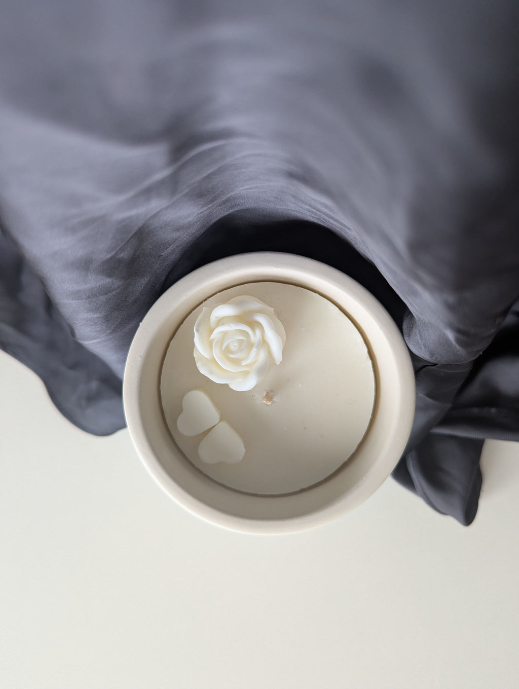 Bougie artisanale parfumée vue du dessus avec cire délicate et composition élégante dune fleur et de deux cœurs collés