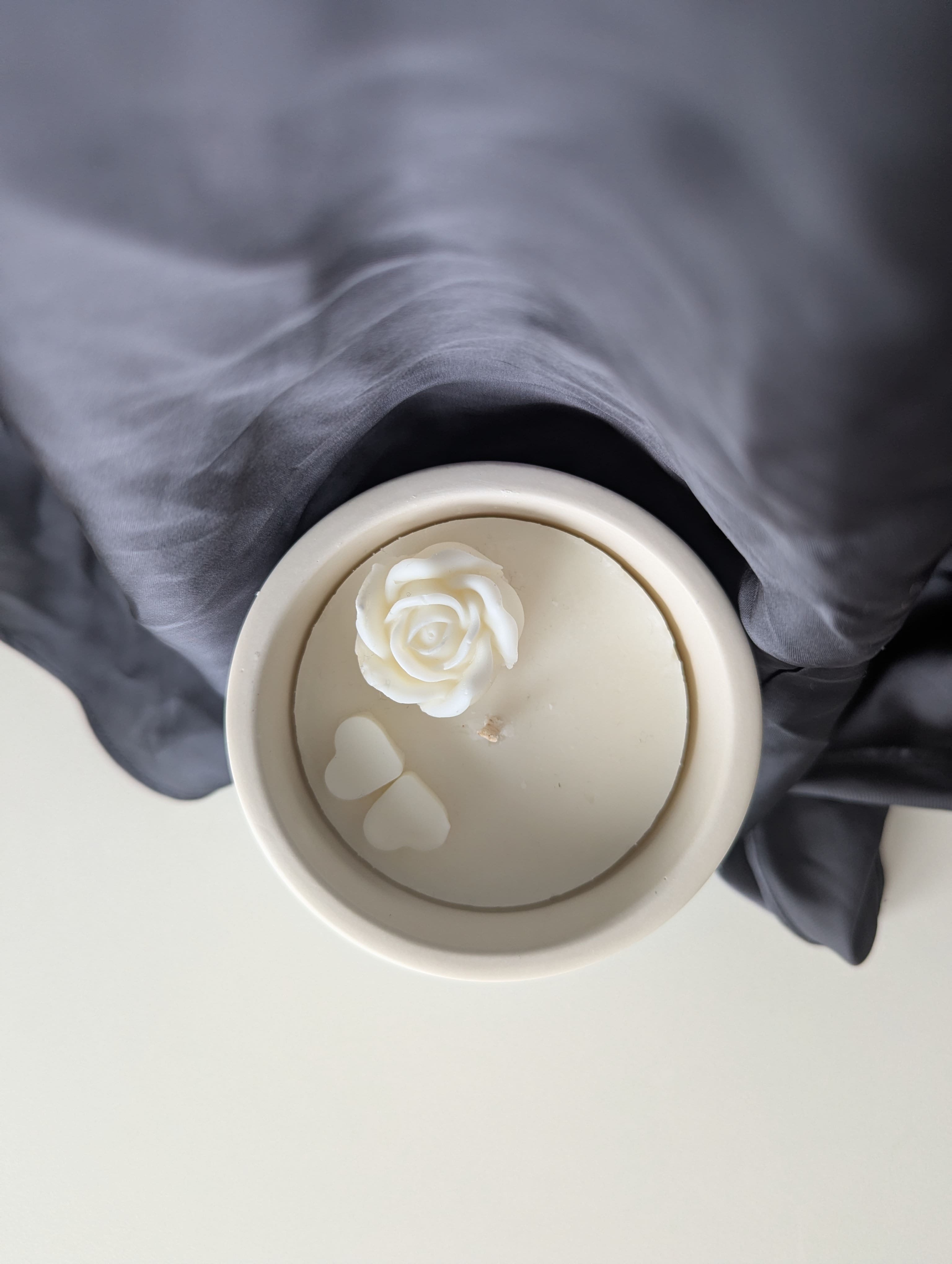 Bougie artisanale parfumée vue du dessus avec cire délicate et composition élégante dune fleur et de deux cœurs collés