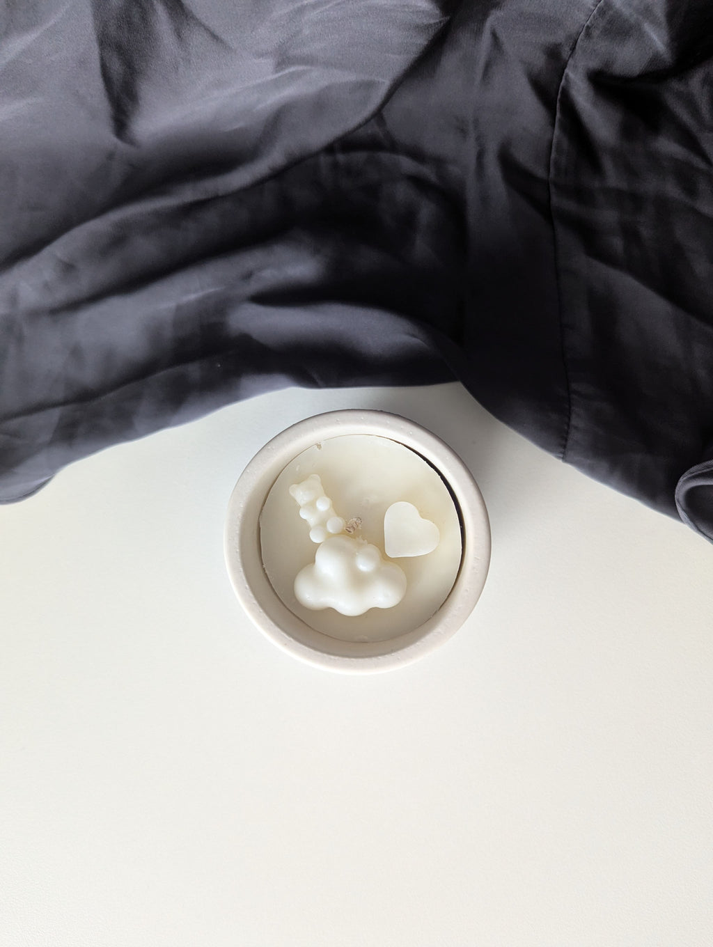 Bougie artisanale parfumée vue du dessus avec cire délicate et composition pour annonce grossesse, naissance, bébé montrant un cœur et un nounours côte à côte et un nuage en dessous