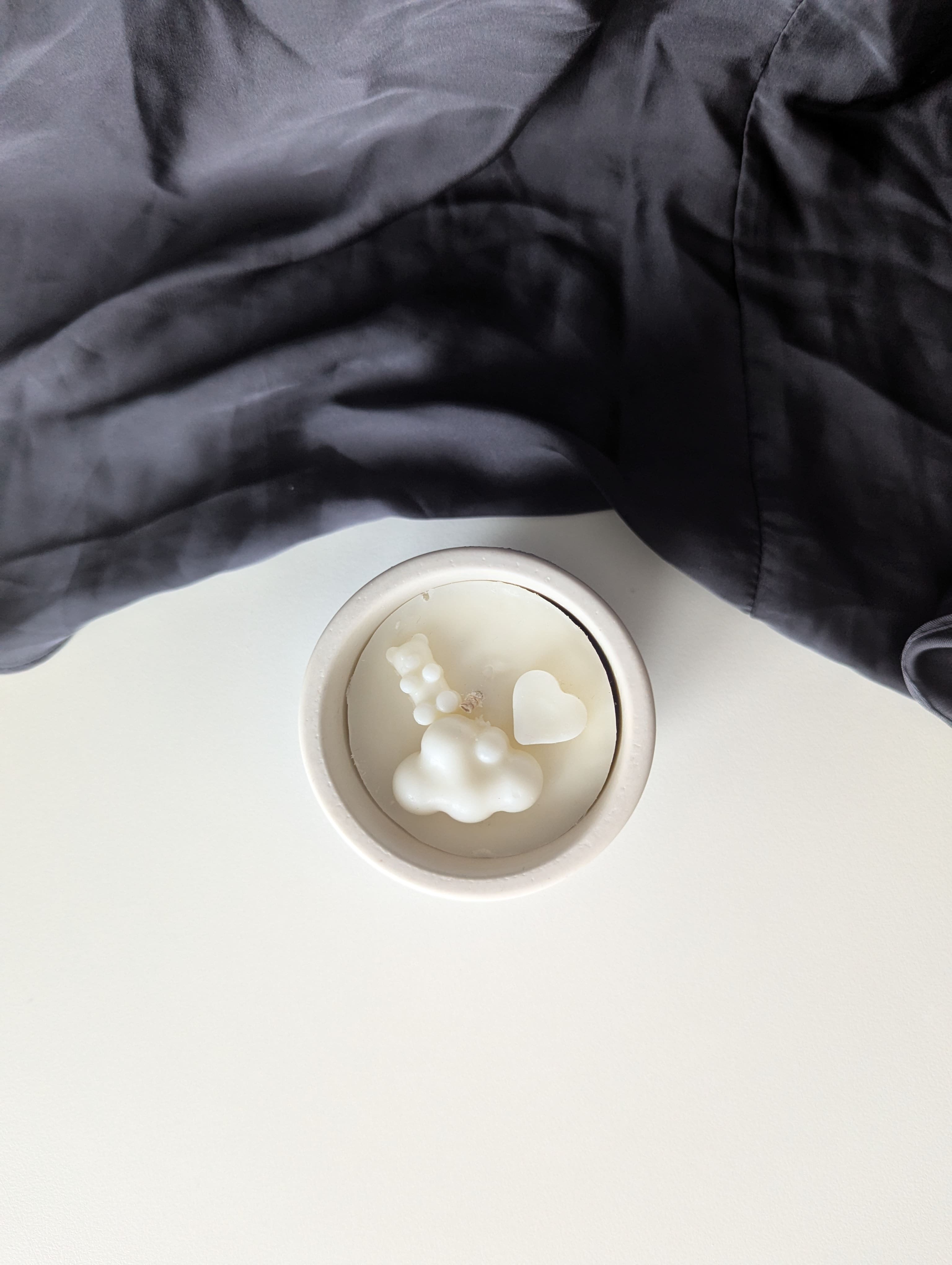 Bougie artisanale parfumée vue du dessus avec cire délicate et composition pour annonce grossesse, naissance, bébé montrant un cœur et un nounours côte à côte et un nuage en dessous