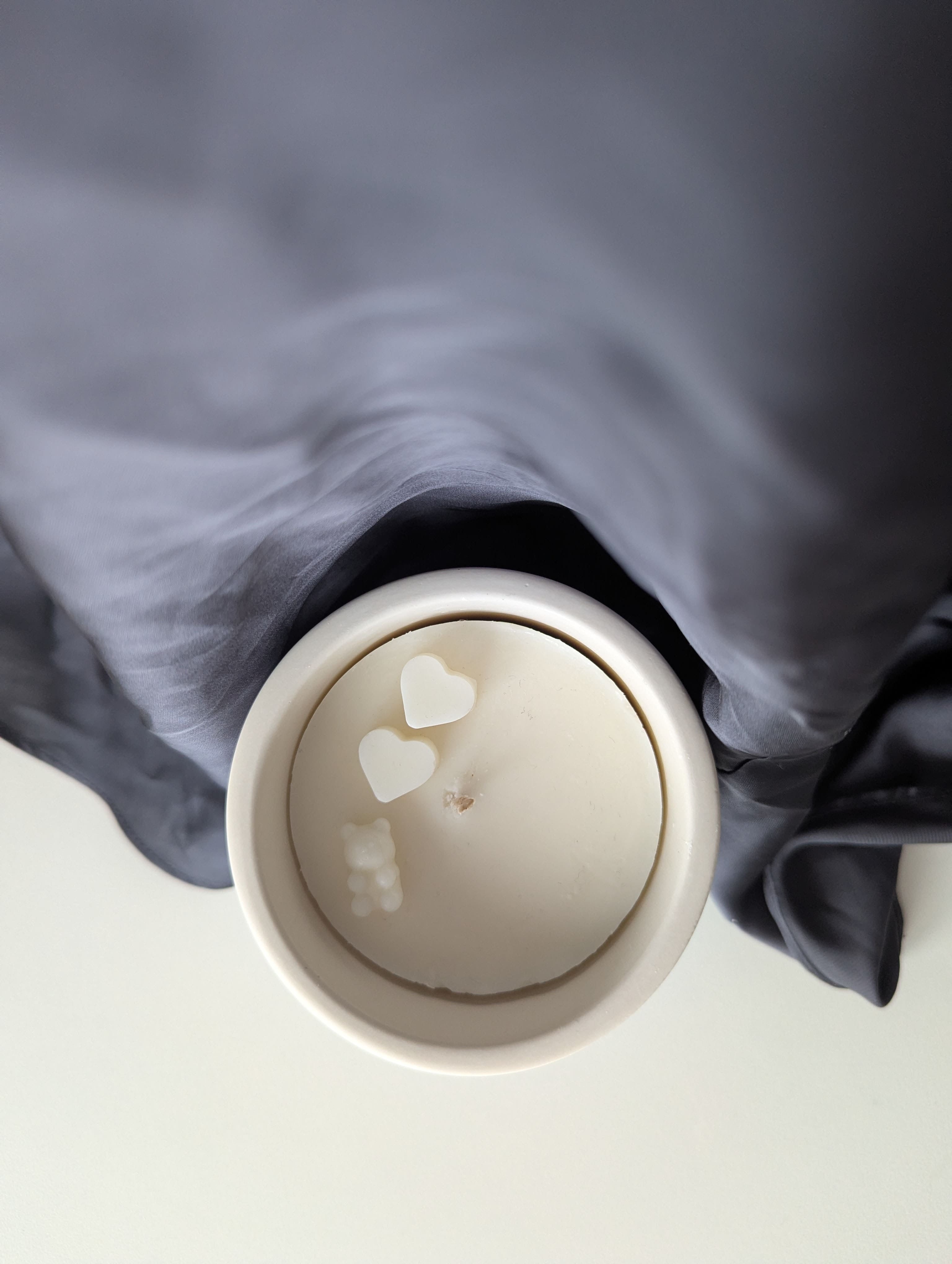 Bougie artisanale parfumée vue du dessus avec cire délicate et composition pour annonce grossesse, naissance, bébé montrant deux cœurs et un nounours.