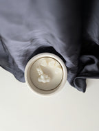 Bougie artisanale parfumée vue du dessus avec cire délicate et composition pour annonce grossesse, naissance, bébé montrant trois cœurs, un nounours et un nuage.