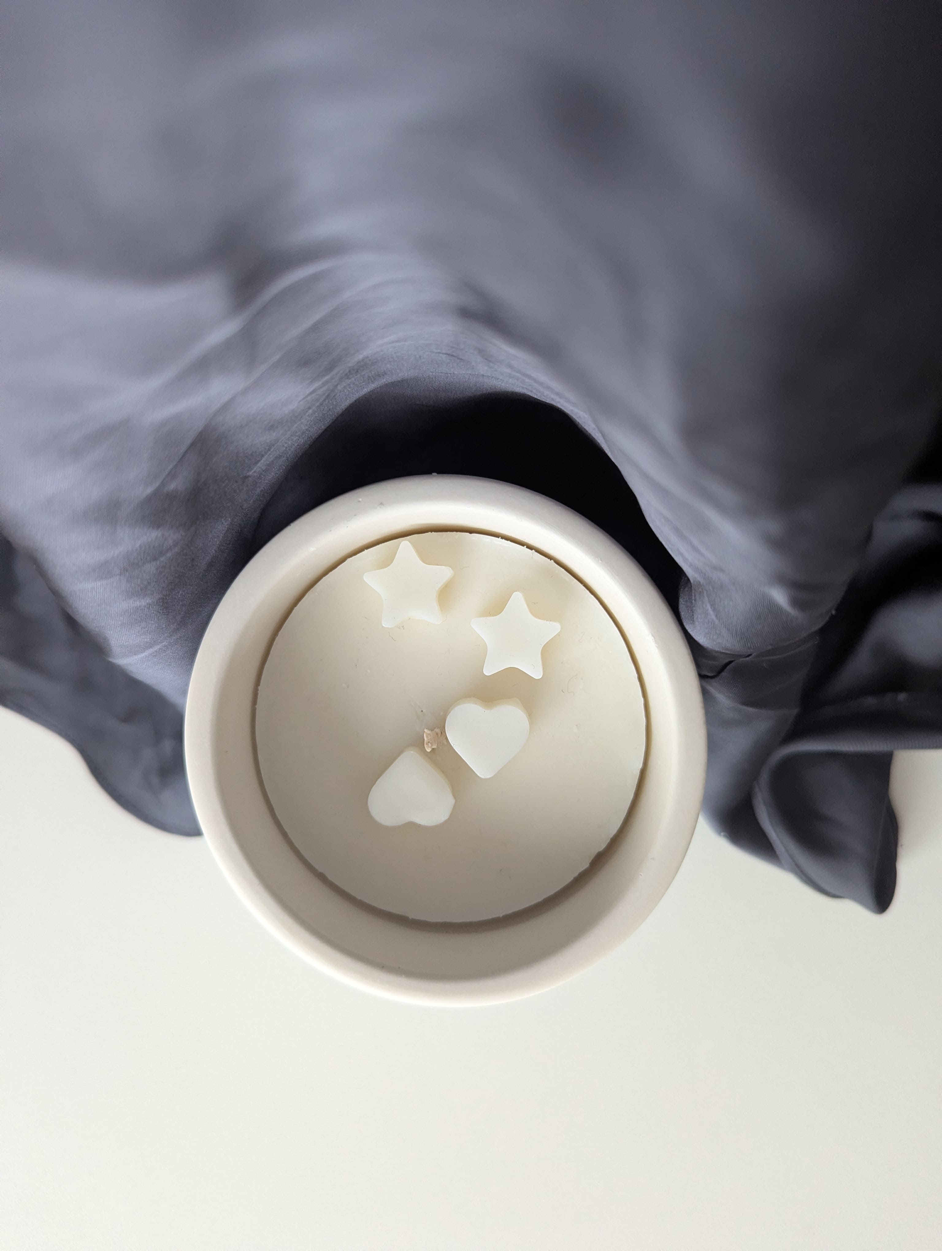 Bougie artisanale parfumée vue du dessus avec cire délicate et composition élégante de deux coeurs face à face et de deux étoiles.