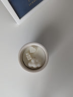 Bougie artisanale parfumée vue du dessus avec cire délicate et composition pour annonce grossesse, naissance, bébé montrant un cœur, un nounours et un nuage