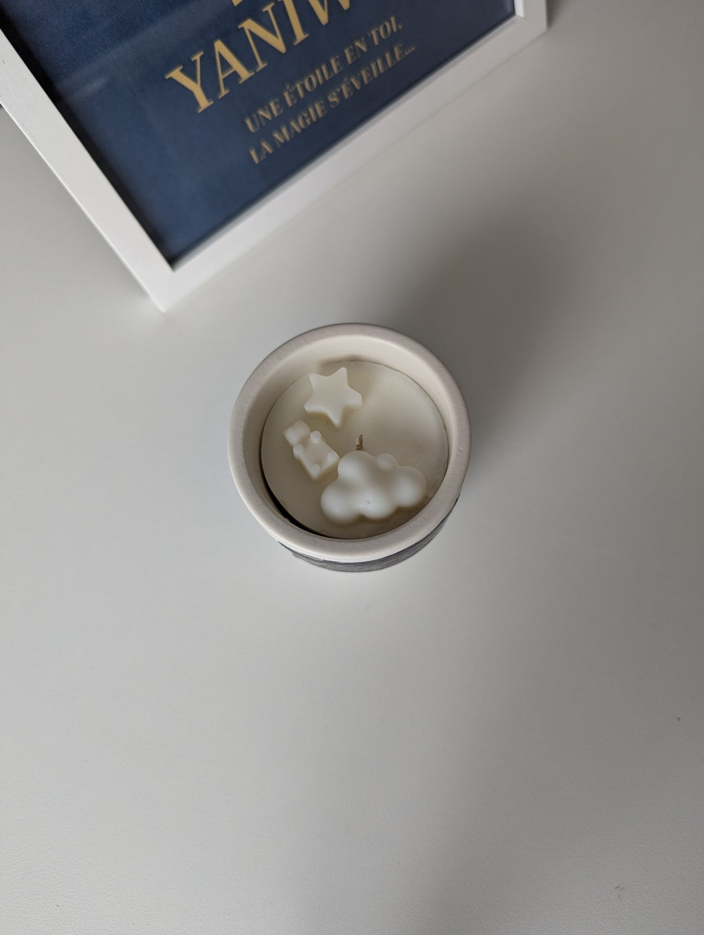 Bougie artisanale parfumée vue du dessus avec cire délicate et composition pour annonce grossesse, naissance, bébé montrant une étoile, un nounours et un nuage