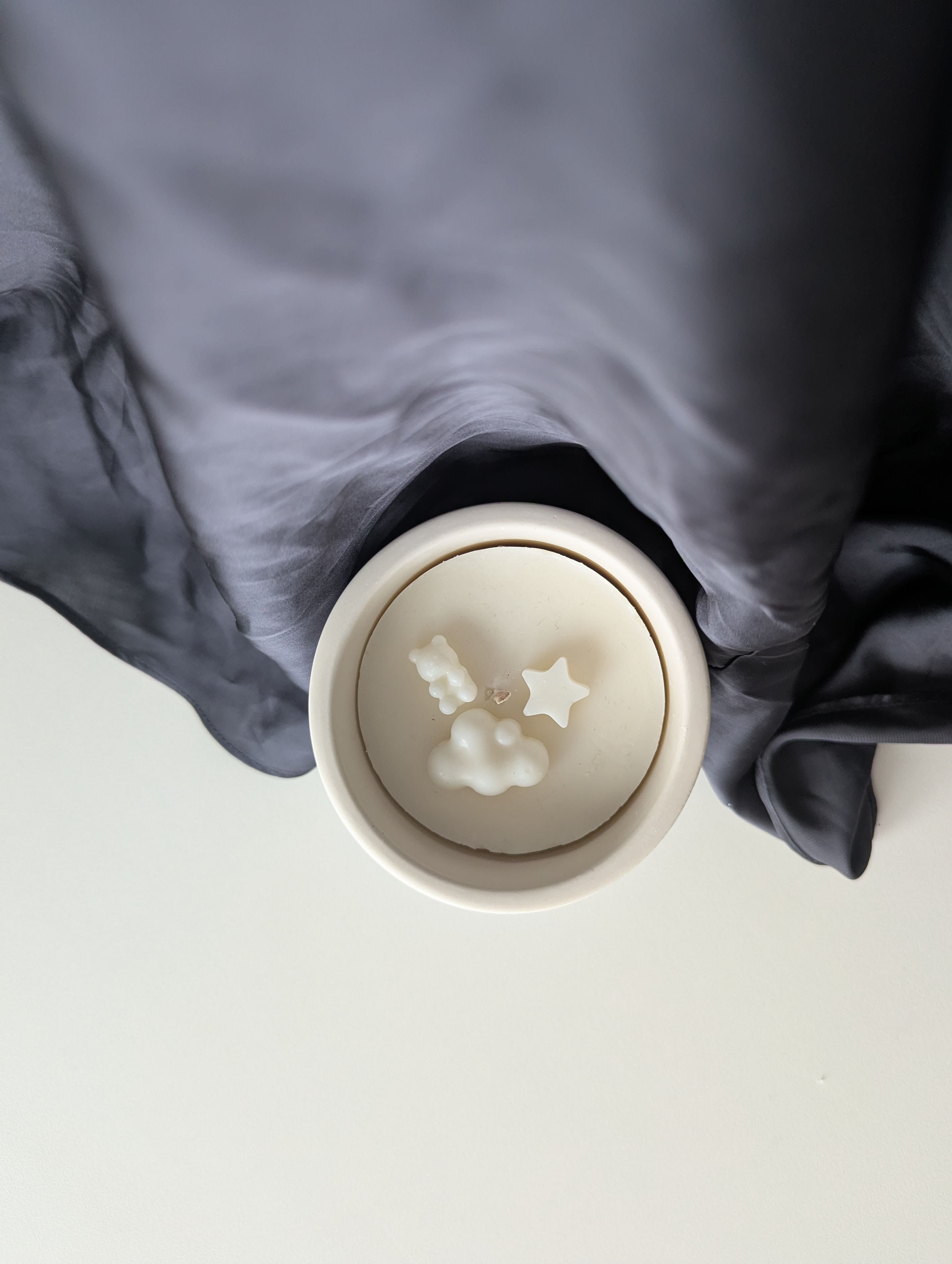 Bougie artisanale parfumée vue du dessus avec cire délicate et composition pour bébé naissance annonce grossesse d’un nuage d’un nounours et d’une étoile à côté