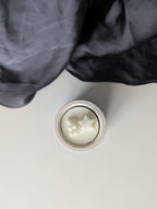 Bougie artisanale parfumée vue du dessus avec cire délicate et composition annonce bébé, grossesse avec un nounours et une étoile